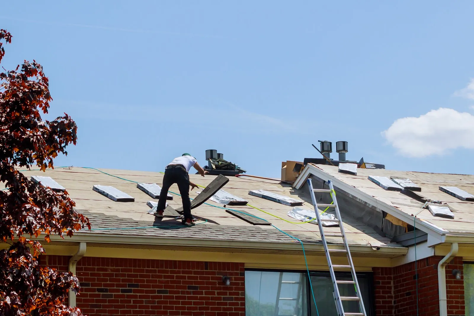 Dakdekker aan het werk op een dak na stormschade, met ladder tegen de gevel