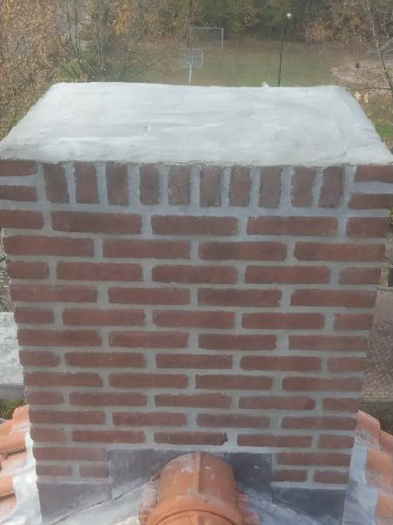 Dezelfde schoorsteen na de reparatie, met nieuw metselwerk en een strakke afdekking